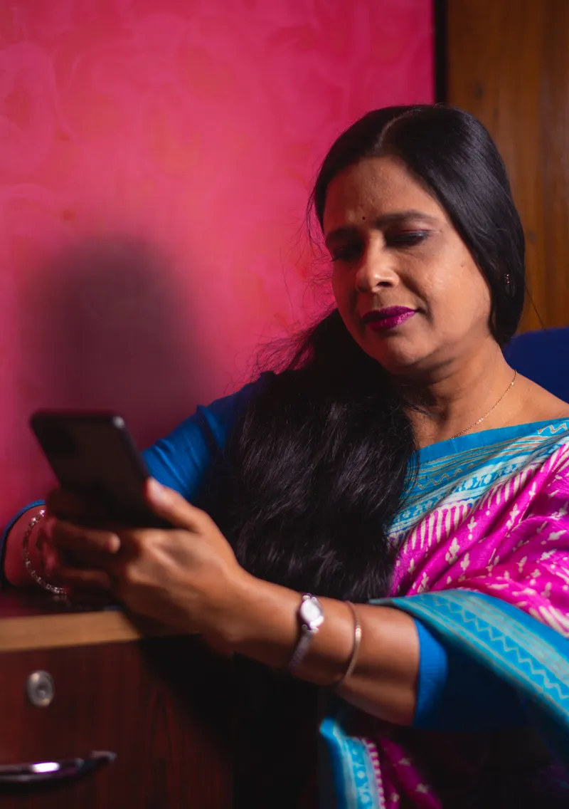 Woman in a saree shopping online and paying on her smartphone, showing ecommerce in Bangladesh