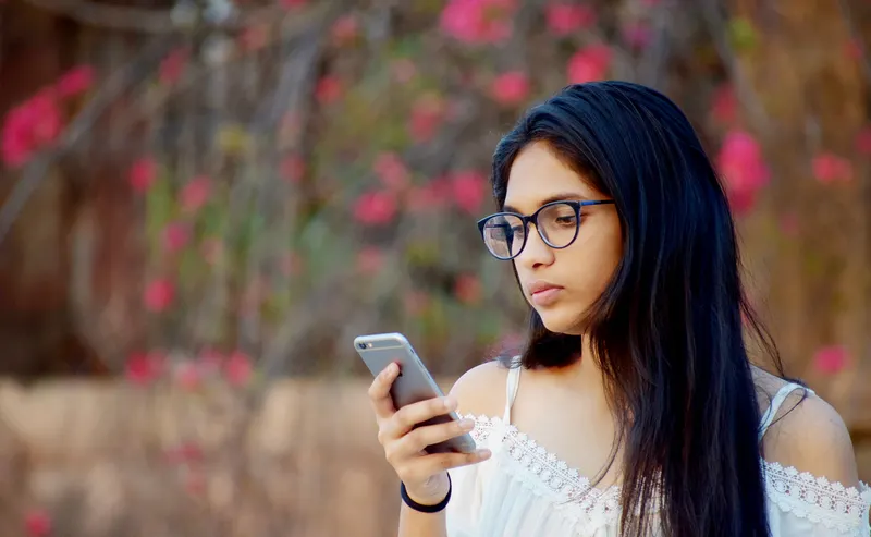 Young woman using a mobile app on her smartphone, built by a mobile app development company in Bangladesh