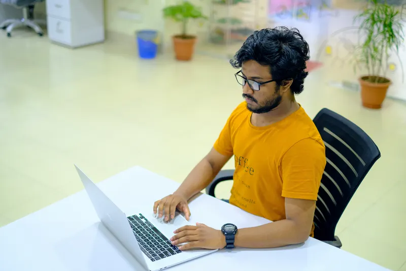 Web developer in Dhaka writing and testing website code on a laptop